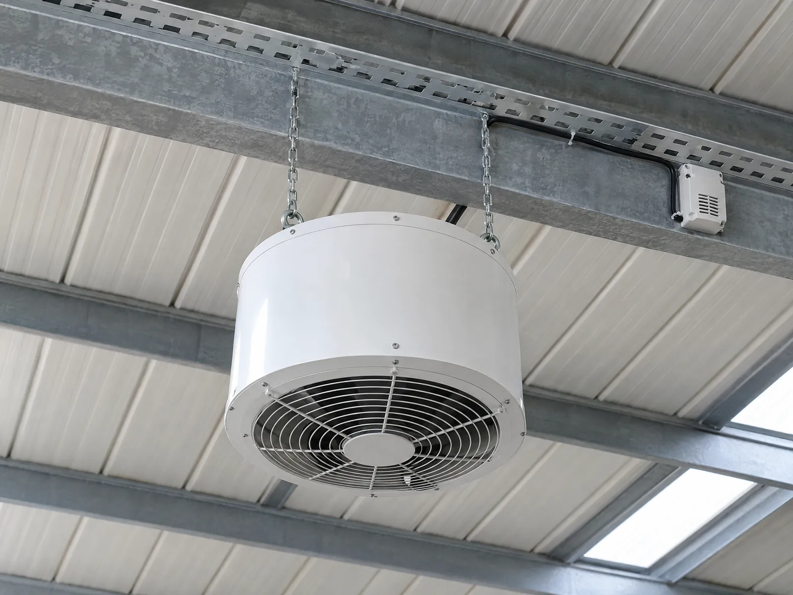 Destratificateur d'air à flux vertical suspendu sous une panne métallique, grille de soufflage tournée vers le sol